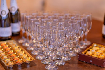 wine glasses arranged on the table in the shape of a triangle,candy in a box and a bottle of champagne