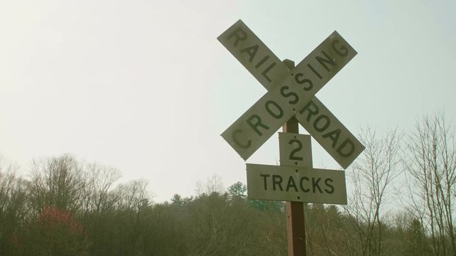 Railroad Crossing Sign with Sun Shining From Behind SLIDE LEFT SLOW MOTION