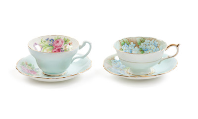 High resolution close-up of two beautiful antique tea cups with saucers isolated on a white background.