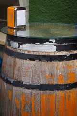 Close-up of an old brown wooden barrel table at a bar or pub. A napkin holder with paper napkins on the barrel table. 