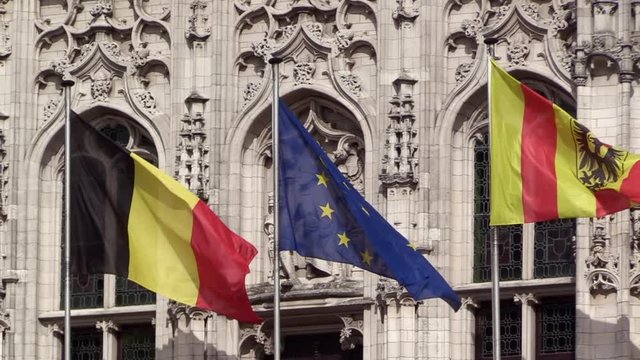 Mechelen, EU and Belgian flag waving in front of Emperor Charles V statue on the town hall of Mechelen, SLO-MO