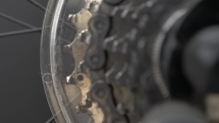 Slow motion pan into moving bicycle chain and gear cogs with low depth of field