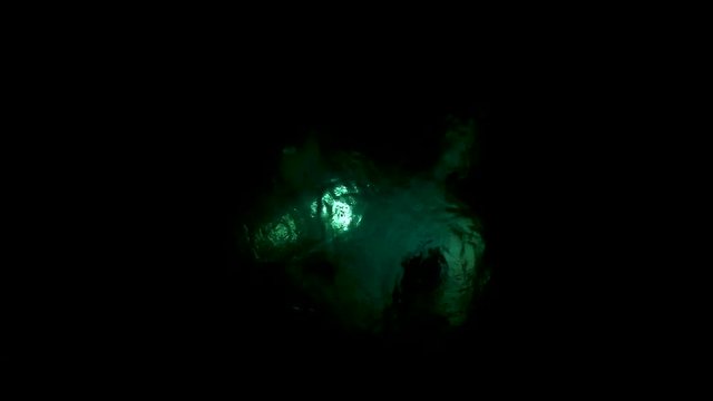 Night time video of scuba divers using underwater lights while diving
