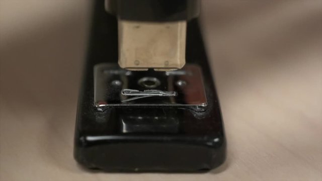 A hand hitting a stapler with no paper in it a bunch of times knocking staples out. In super slow motion.