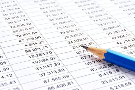 Blue pencil on a sheet of white paper with printed financial numerical data table with columns. Concept for accounting, budget, profit, tax and financial review. Image with selective focus 
