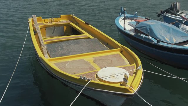 Small bright yellow plastic lake boat moored at seaside harbor plywood panels slow motion