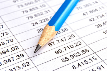 Fototapeta premium Blue pencil on a sheet of white paper with printed financial numerical data table with columns. Concept for accounting, budget, profit, tax and financial review. Image with selective focus 