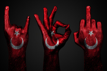 a set of three hands with a painted flag Turkey show middle finger, goat and Okay, a sign of aggression, protest and approval on a dark background.