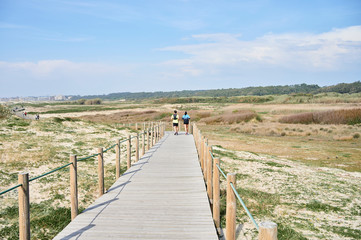 couple runing on Wooden footwalk over the dunes in portugal near the beach