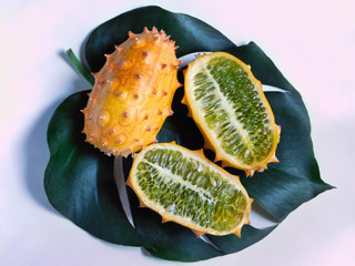 Whole and halves of a kiwano fruit on leaf