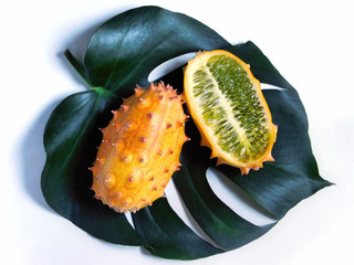 Whole and half kiwano fruit on leaf