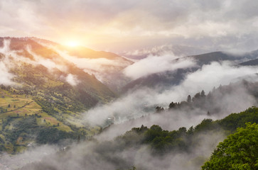 Summer mountain panorama. Small wooden house cottage and barn on green mountain valley on bright foggy sky, clouds and mountain