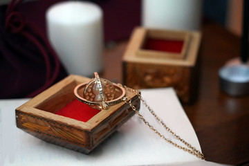 Magical golden round mascot with a chain in wooden box on the book on a blurred background. Occult, esoteric, fortune-telling and wicca concept. Mystic and vintage background.