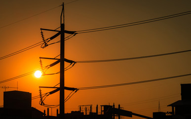 High voltage electric pole and transmission lines in the city. Electricity pylons at sunset. Power...