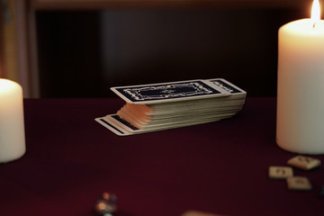 Composition of esoteric objects used for healing, meditation, relaxation and purifying. Tarot cards, ancient runes and white candles on a dark table. Occult, esoteric, divination and wicca concept.