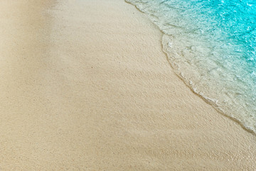 Fototapeta na wymiar wave of blue ocean on sandy beach with copy space & design for Background