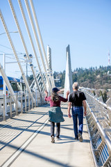 Elderly couple man and woman take walk Tilikum Crossing Bridge actively talking to each other