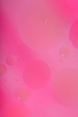 Blurred abstract background. Macro shot of oily liquid. Circles and wavy lines of different sizes of delicate pink color. Blur, vertical, a lot of free space for text, nobody, macro. Concept of design