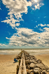 A jetty protruding into the ocean with a beautiful sky as the background.