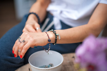 The hands of the girl touch the handmade jewelry. Girl and jewelry. Handmade woman decorating stones close up.