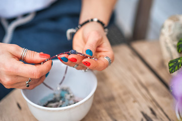 The hands of the girl touch the handmade jewelry. Girl and jewelry. Handmade woman decorating stones close up.