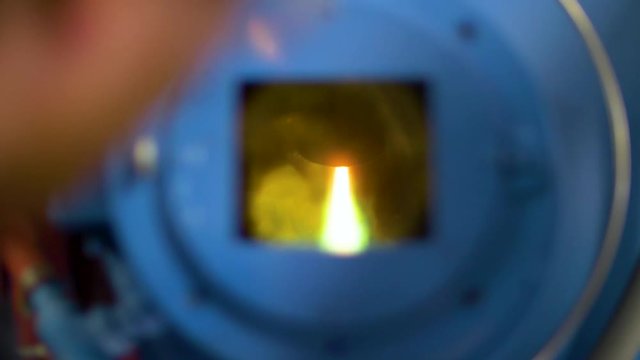 Man watching through the window of plasma arc furnace melting metal