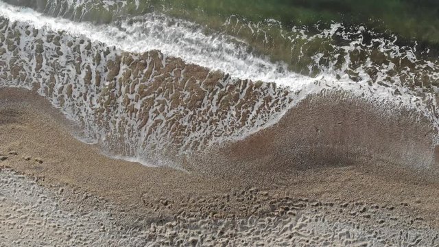Beautiful 4K beach aerial - a bird's eye view of waves crashing from above.