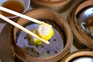Close up Cantonese Shumai (Siu Mai) Dim Sum, shrimp & pork Chinese steamed dumplings wrap by yellow wonton wrapper (Kanom Jeeb in Thai) in bamboo basket in dim sum set