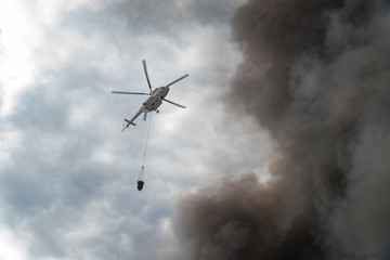 Fototapeta na wymiar Rescue helicopter drops water extinguishes the fire