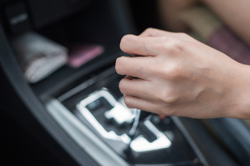 Driver woman hand holding automatic transmission in car.