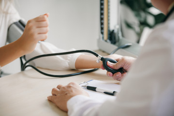 Doctor using stethoscope take a tap on the patient's arm and pressing pressure gauge button.