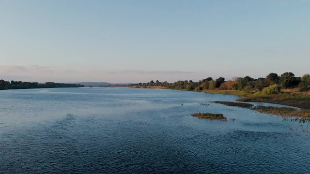 Traveling over a red metal bridge, sunset time, in Goleg&atilde;, Santar&eacute;m, Portugal. Green landscape and river views. Soft and bright light. Chamusca