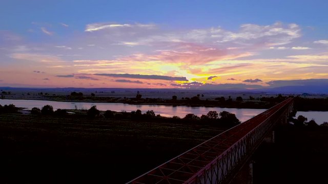 Traveling over a red metal bridge, sunset time, in Goleg&atilde;, Santar&eacute;m, Portugal. Green landscape and river views. Soft and bright light. Chamusca