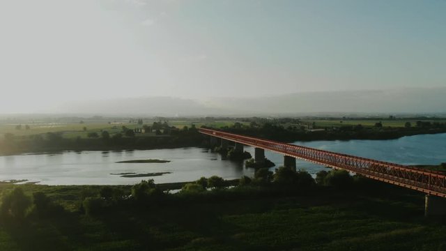 Traveling over a red metal bridge, sunset time, in Goleg&atilde;, Santar&eacute;m, Portugal. Green landscape and river views. Soft and bright light. Chamusca