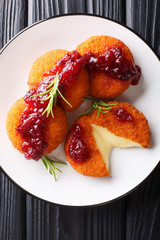Gourmet appetizer Camembert in breading served with cranberry sauce and rosemary close-up on a plate. Vertical top view