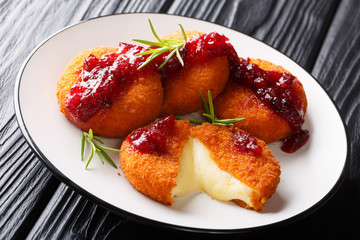 Freshly cooked camembert in breading served with cranberry sauce and rosemary close-up on a plate. horizontal