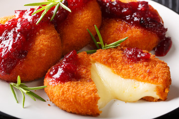 Gourmet appetizer Camembert in breading served with cranberry sauce and rosemary close-up on a plate. horizontal