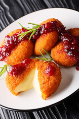 Delicious Baked Camembert Cheese Breaded with Cranberry Sauce and Rosemary closeup on a plate. vertical