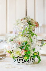 Floral arrangement with roses, dahlias and iris flowers inside a vintage bird cage.