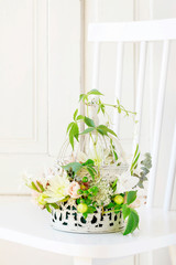 Floral arrangement with roses, dahlias and iris flowers inside a vintage bird cage.