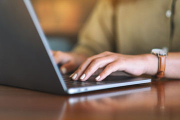 Closeup image of woman's hands using and typing on laptop computer keyboard