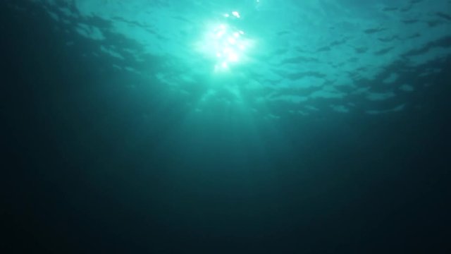 Underwater background video of sunburst on ocean surface with sunbeams