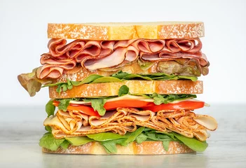 Selbstklebende Fototapeten Fresh double layered sandwich with ham, lettuce, tomatoes, cheese on a toast bread. Food background. © Inna Zakharchenko