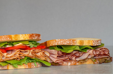 Freshly made deli style sandwich with lettus, several different kinds of vegetables, tomatoes, cheese, meats similar to ham, chicken or turkey.