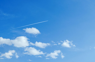 plane flying across the blue sky with clouds
