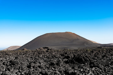 Timanfaya National Park, mountains of fire Lanzarote, Canary Islands, Spain. Unique panoramic view of spectacular lava river flows from a huge volcano crater creates a lunar landscape on planet earth.