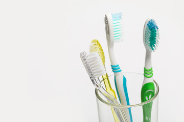 Set of toothbrushes in glass on white background.