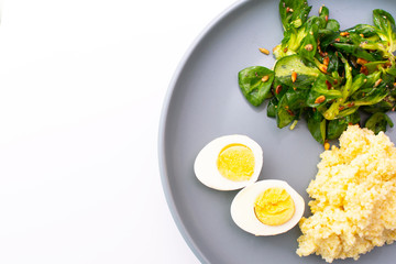 Millet porridge with salad and eggs on a plate on a white background