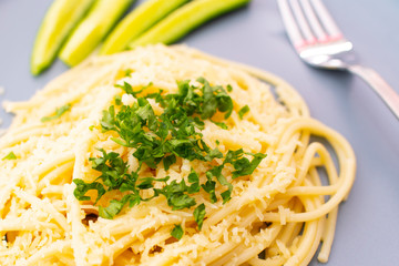 Spaghetti sprinkled with herbs with cucumber on a plate on a white background