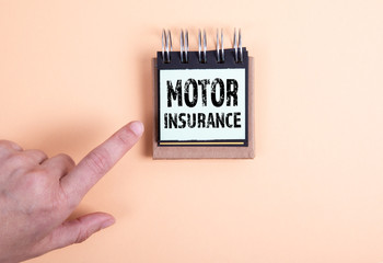 Motor Insurance concept. Woman's hand and note pad on an orange table